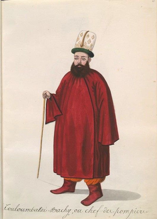 A full-body portrait of a man in a red robe and tall hat, holding a cane.