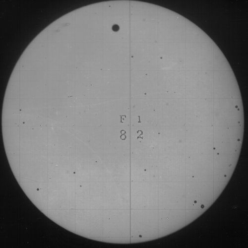 A circular image of the sun with sunspots and markings.