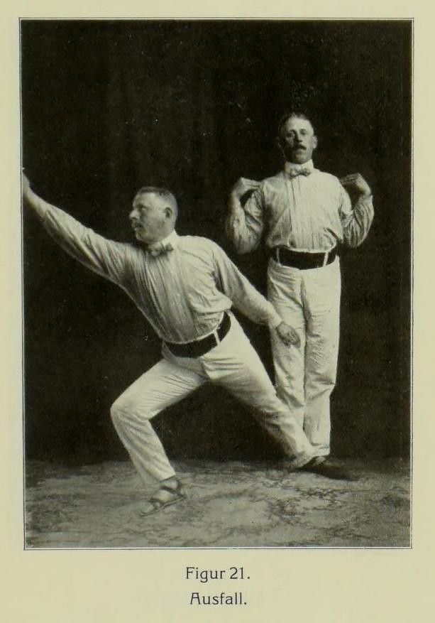 Vintage black and white photograph of two men in formal attire demonstrating a gymnastic exercise.