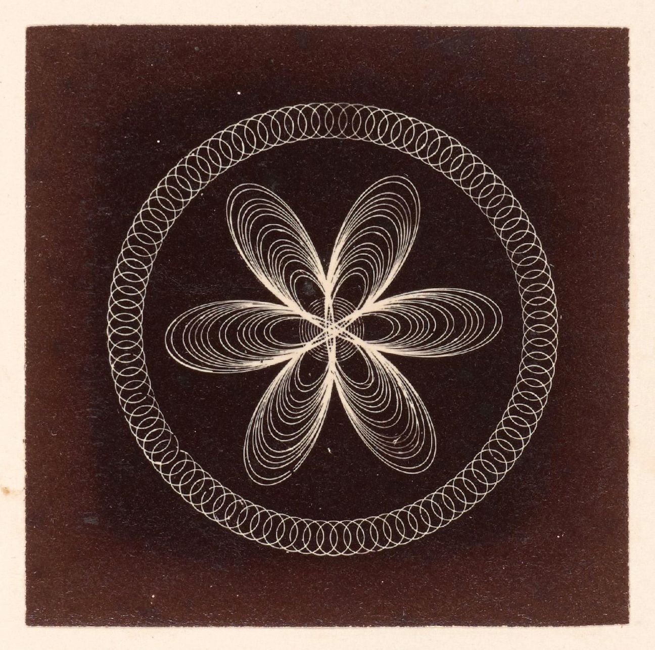 A square-shaped photograph featuring a complex geometric pattern against a dark background. The central design consists of a four-petal flower-like shape created by swirling, curved lines. Surrounding this central design is a larger circle composed of numerous smaller, closely spaced circles.