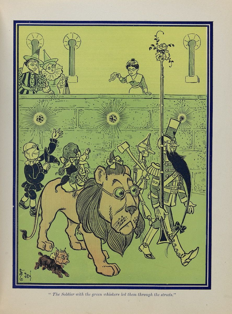 A vintage illustration of a procession led by a soldier with green whiskers, followed by a lion, scarecrow, tin woodman, and Dorothy, moving down a street lined with buildings and onlookers.