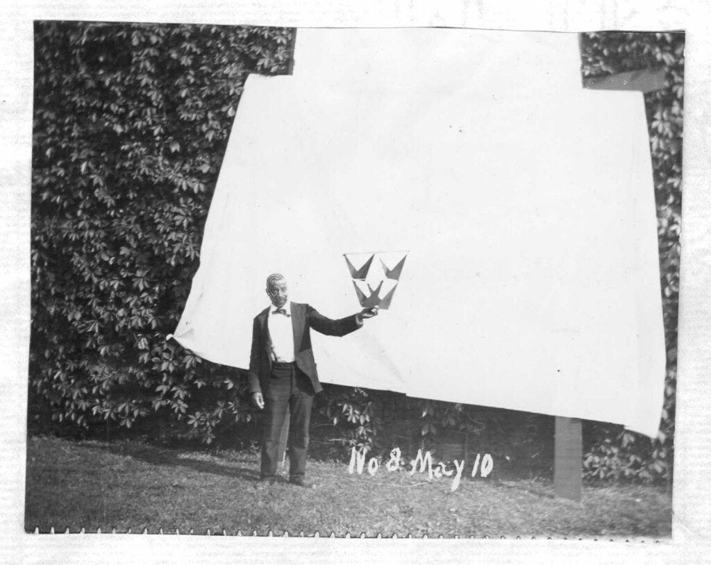 Vintage black and white photograph of a man releasing birds in front of a wall.