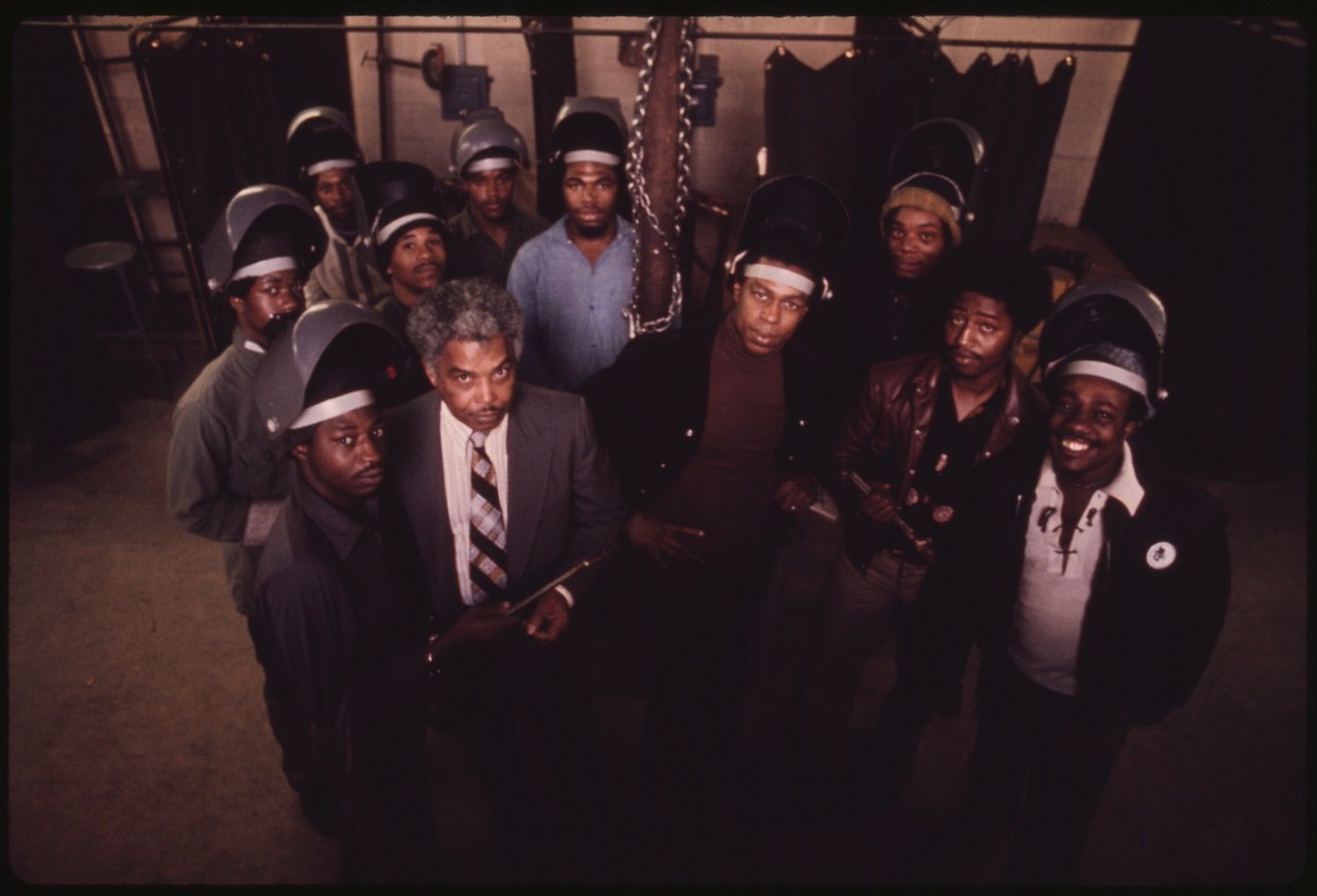 A high-angle portrait of a group of African American men, likely a band, wearing matching hats and various outfits. They are looking directly at the camera with serious expressions.