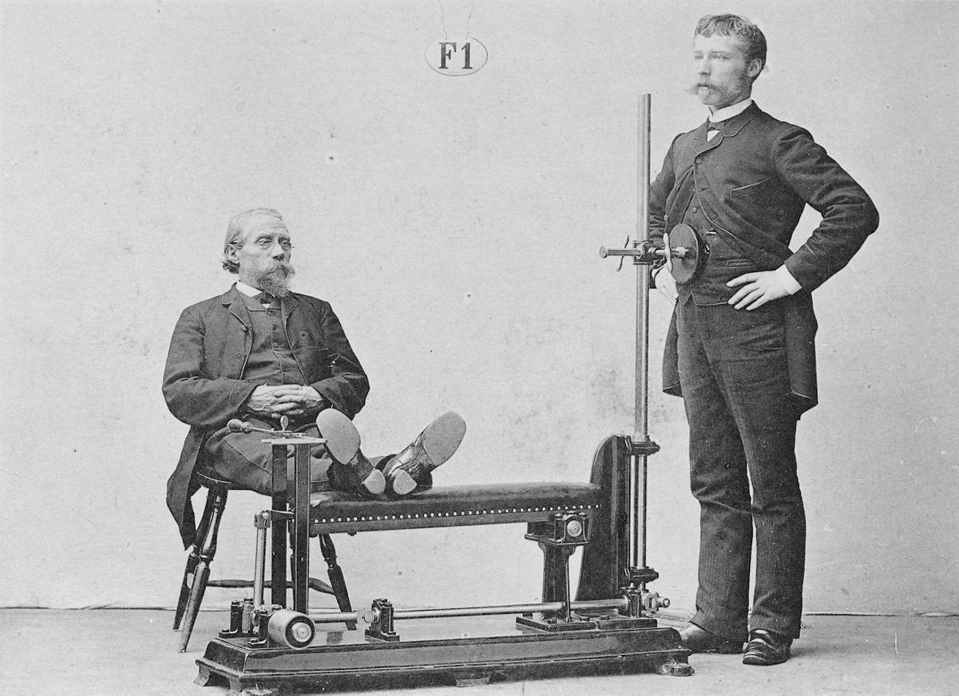 A vintage black and white photograph of a medical device and two men.