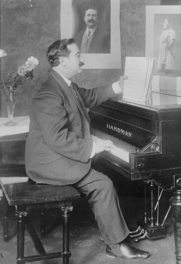 A vintage black and white photograph of a man seated at a piano.