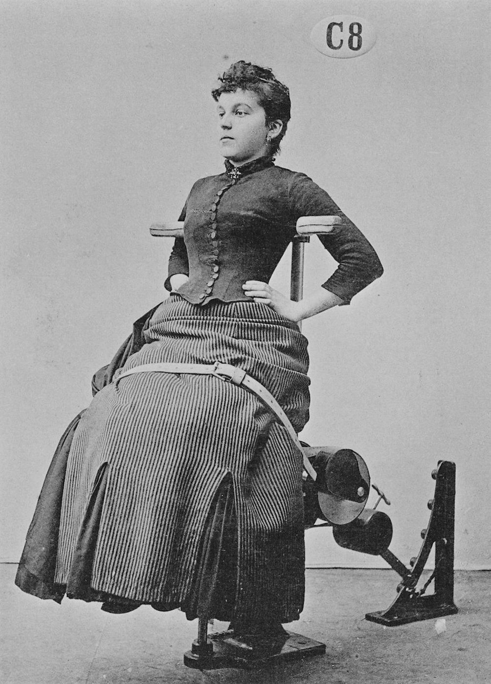 A vintage black and white photograph of a woman seated on a peculiar contraption.