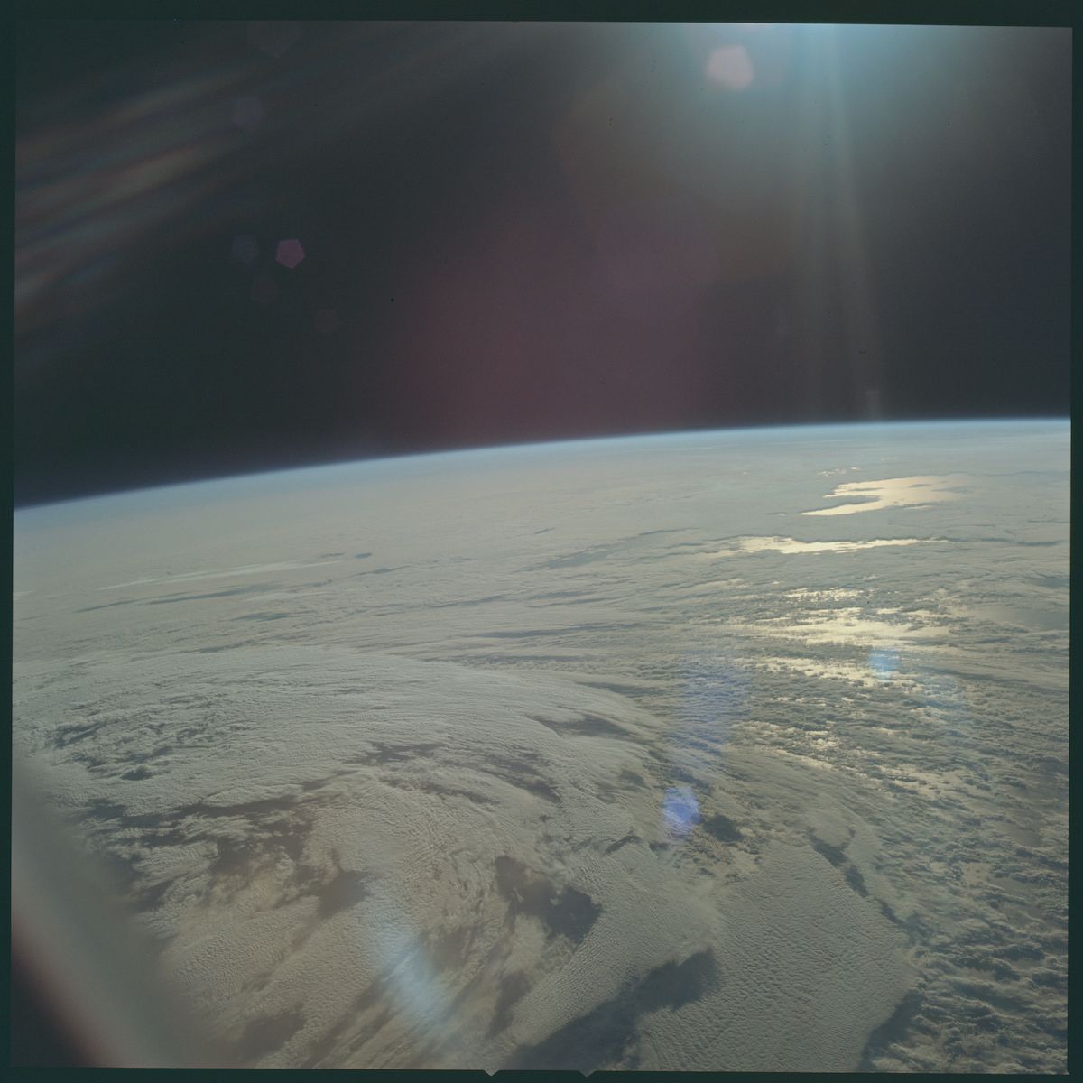 A view of Earth from space, showing the curvature of the planet, a vast expanse of clouds, and the dark blackness of space.