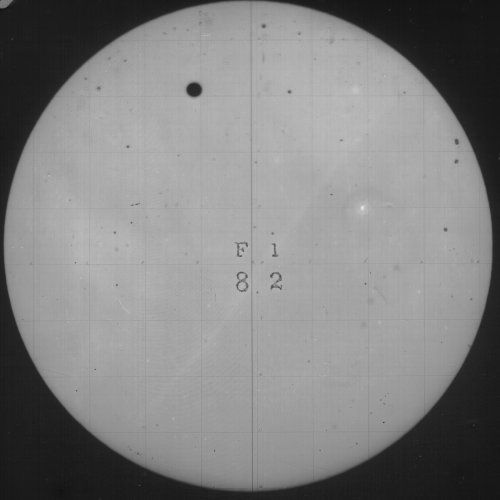 A circular image of the sun with a sunspot and a grid pattern.