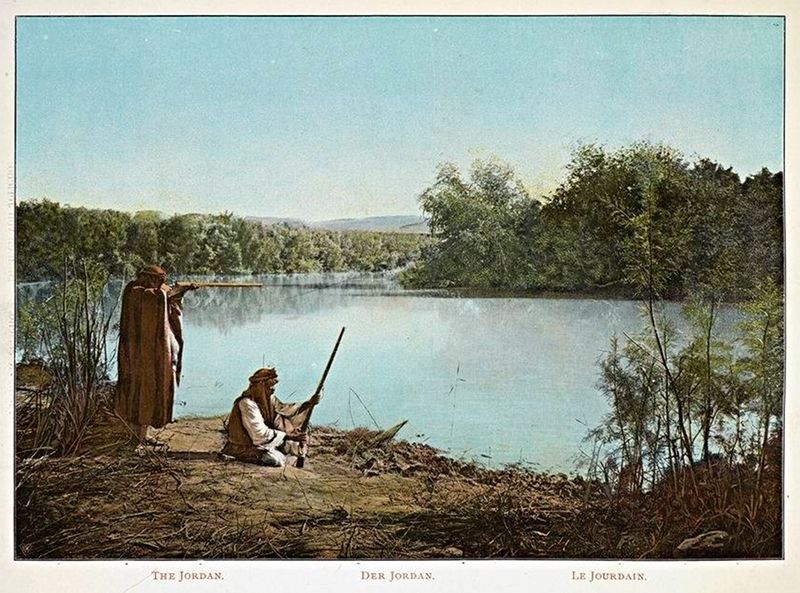Vintage colorized photograph of the Jordan River with two figures fishing or hunting on the bank.