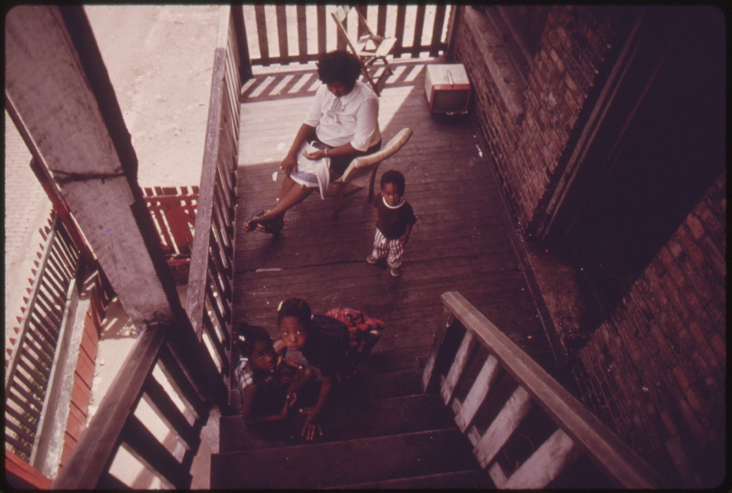 A high-angle view of a porch and stairs with a woman and two children.