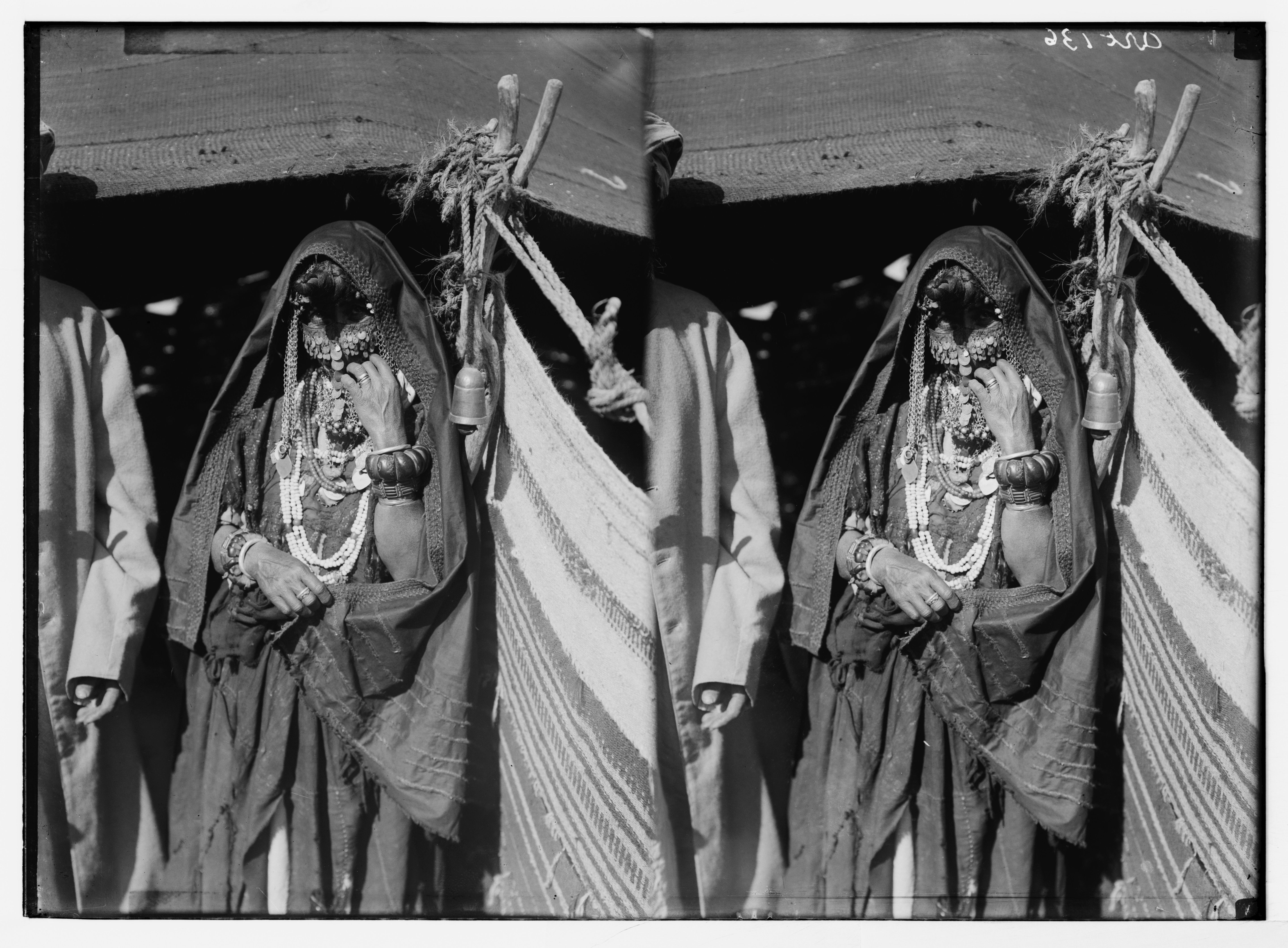 Stereoscopic photograph of a person in traditional clothing, adorned with jewelry and holding ceremonial items.