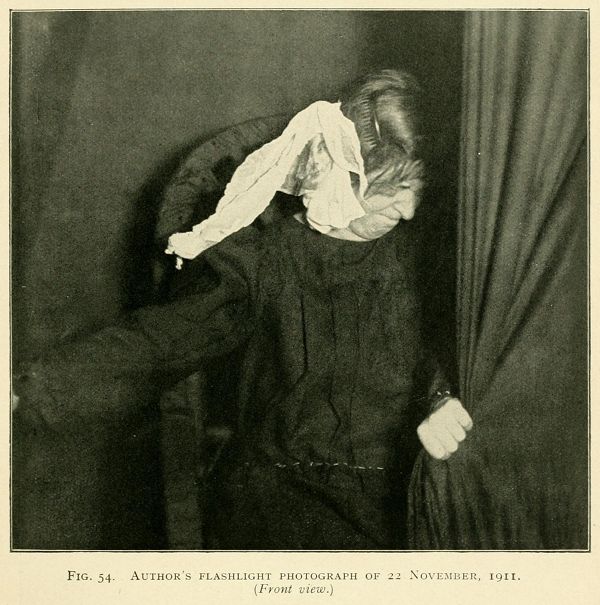 A vintage black and white photograph of a person with a scarf wrapped around their head, taken in 1911.