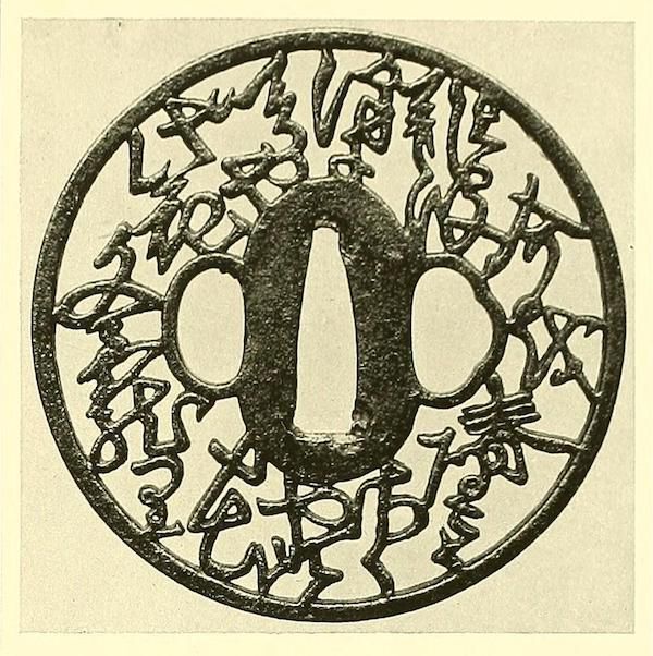 Close-up of an antique Japanese tsuba with intricate floral and character designs.