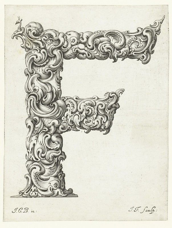 A detailed black and white engraving of the letter 'T' intricately decorated with ornate, swirling foliage and floral patterns.