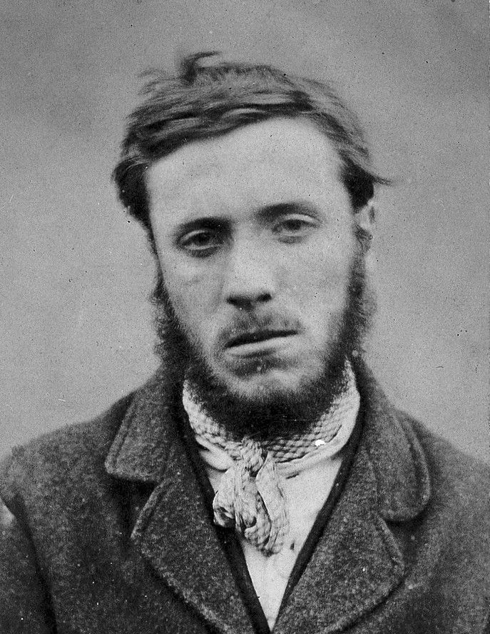 Vintage black and white portrait of a man with a beard wearing a coat and scarf.