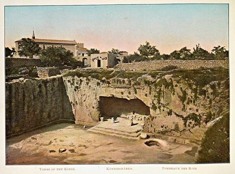 A historical site known as the Tombs of the Kings, with a large, excavated area revealing ancient tombs carved into a cliff face.