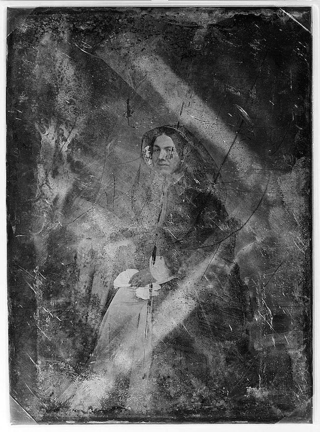 A daguerreotype of a woman with scratches and abrasions.