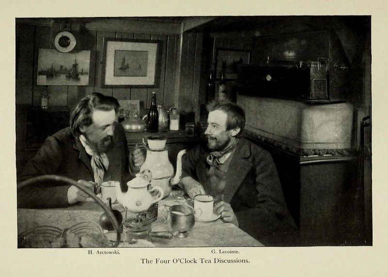 A vintage black and white photograph of two men having a tea discussion.