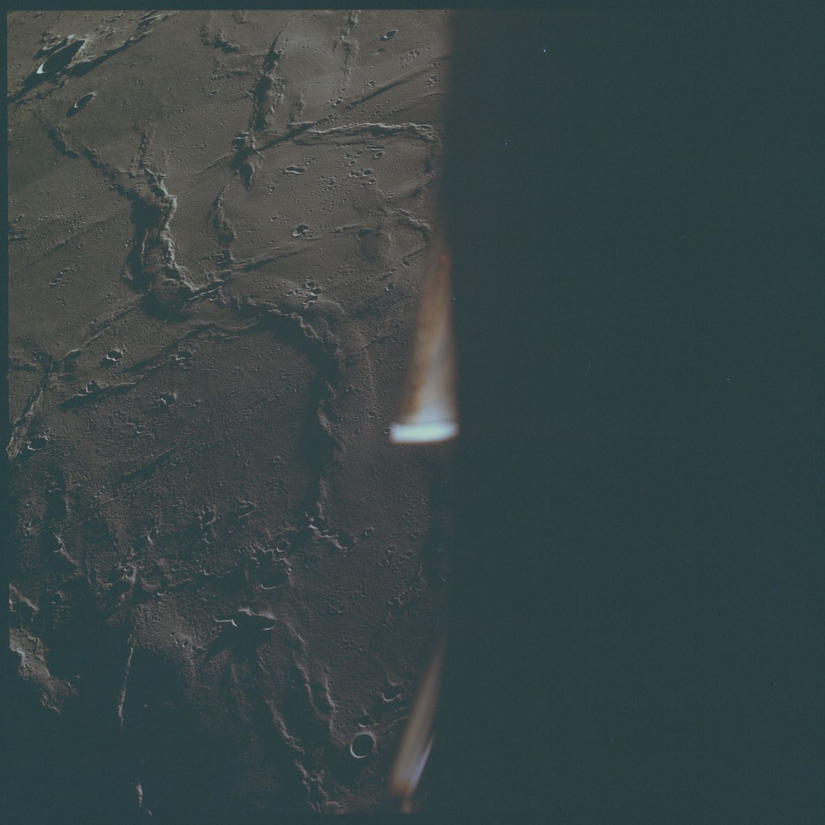 A dark, textured rock surface with a vertical beam of light cutting through the darkness.