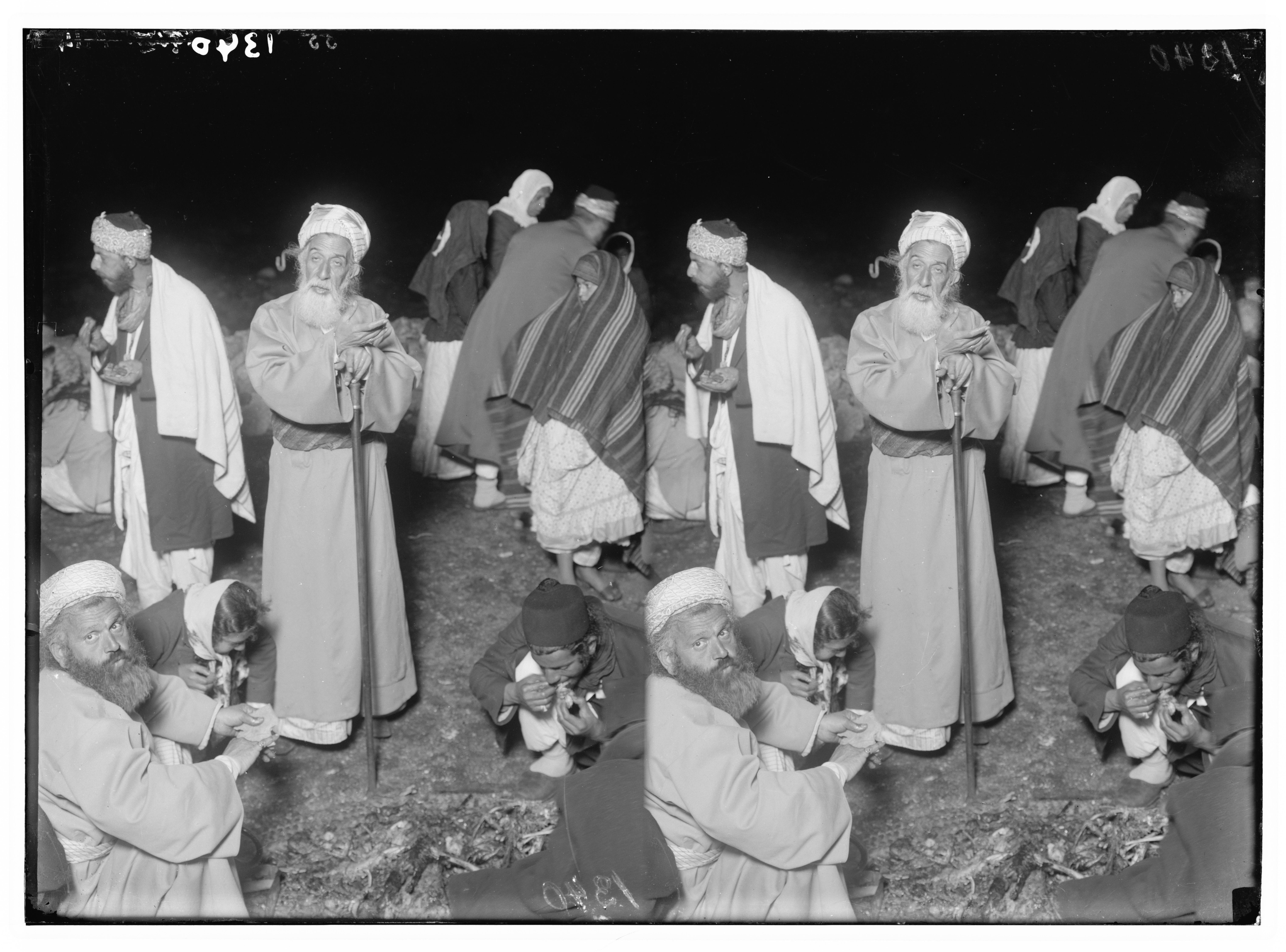 A black and white photograph of a group of men in robes and turbans engaged in a religious ceremony outdoors.