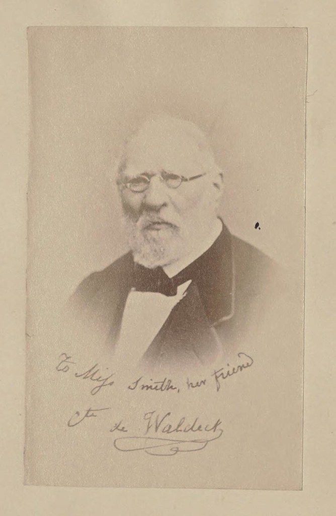 Sepia-toned portrait of a man with a beard and glasses, with a handwritten inscription below.