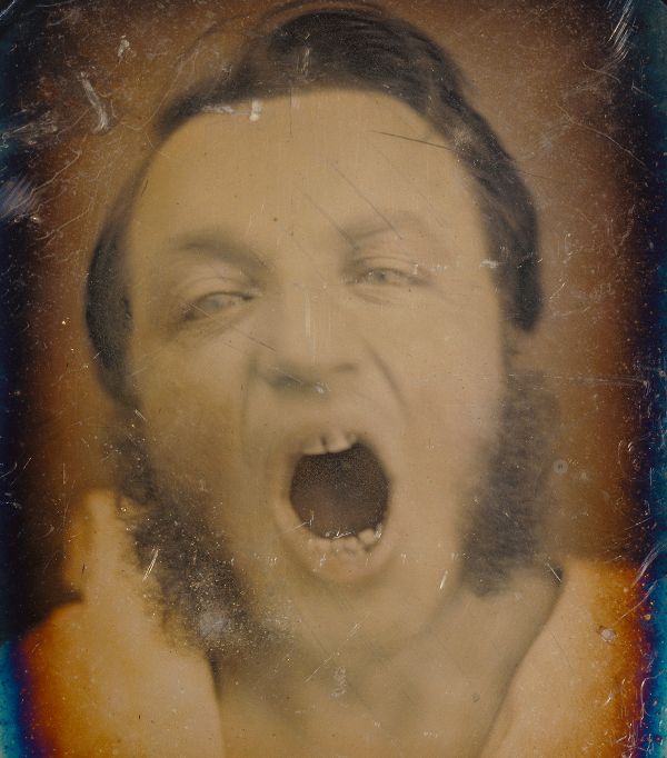 Vintage-style portrait of a man screaming with hands raised to his face.