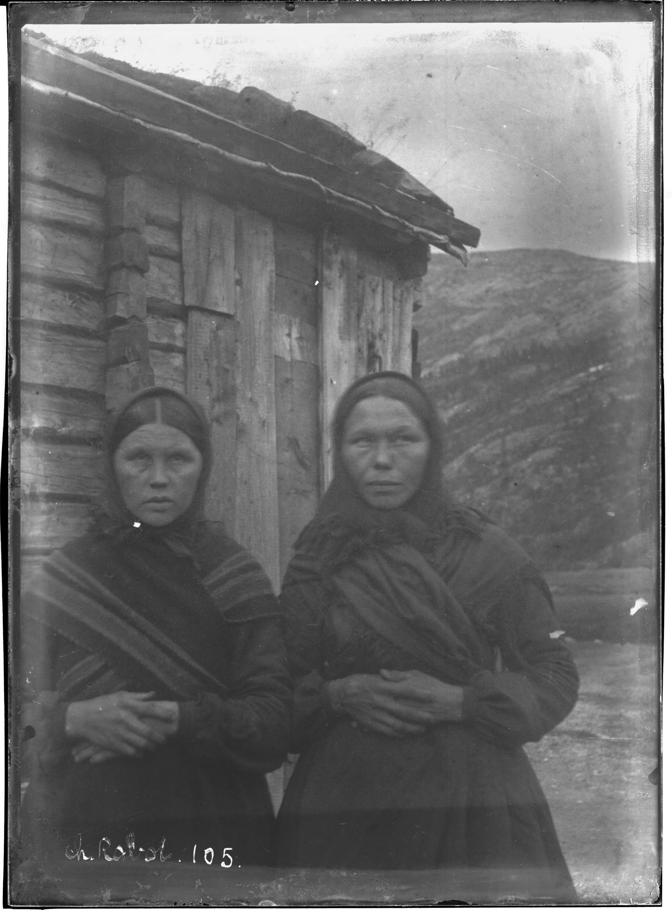A black and white photograph from 1905 featuring two women standing in front of a rustic wooden building.