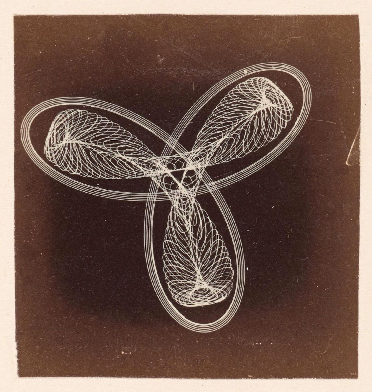 Vintage photograph of an abstract design with swirling lines and circular shapes against a dark background.