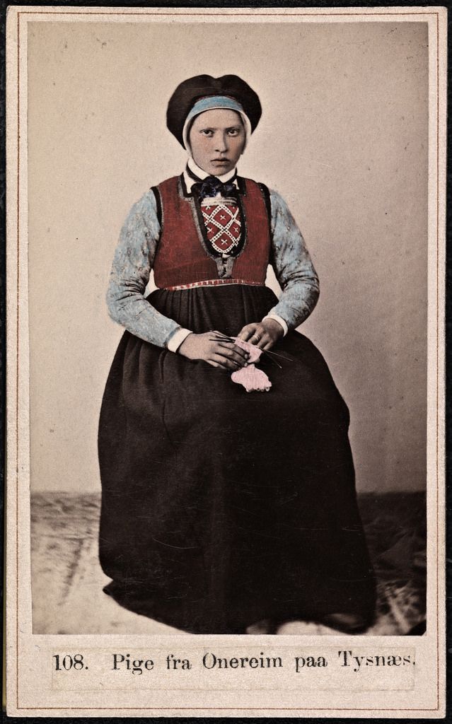 Vintage photograph of a young woman in traditional Norwegian folk costume, holding knitting needles and yarn.