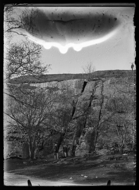 A black and white photograph of a rocky landscape with trees and people.