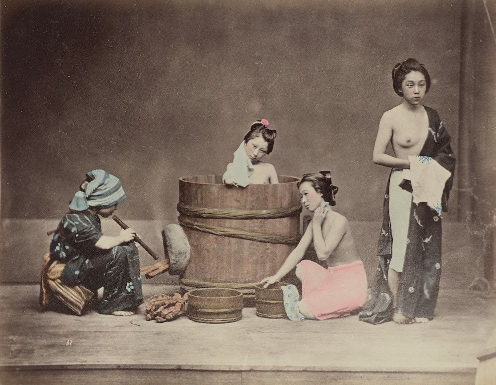 Vintage photograph of Japanese women and a child bathing in a wooden tub.