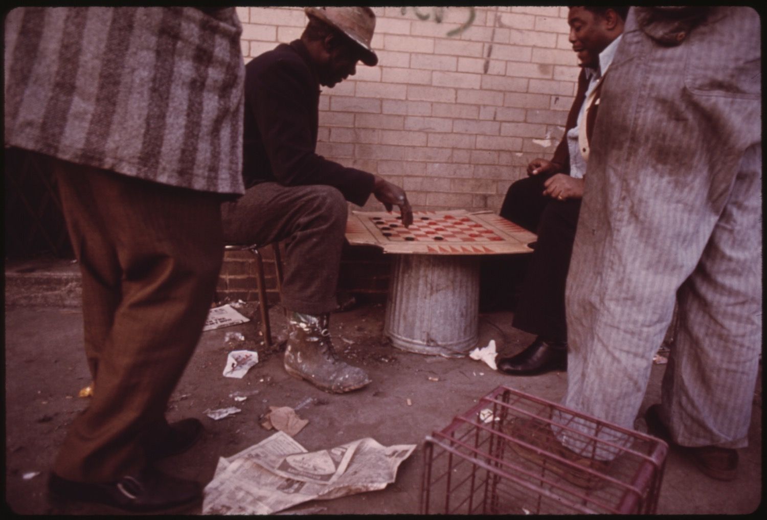 Three men playing checkers on a street corner.