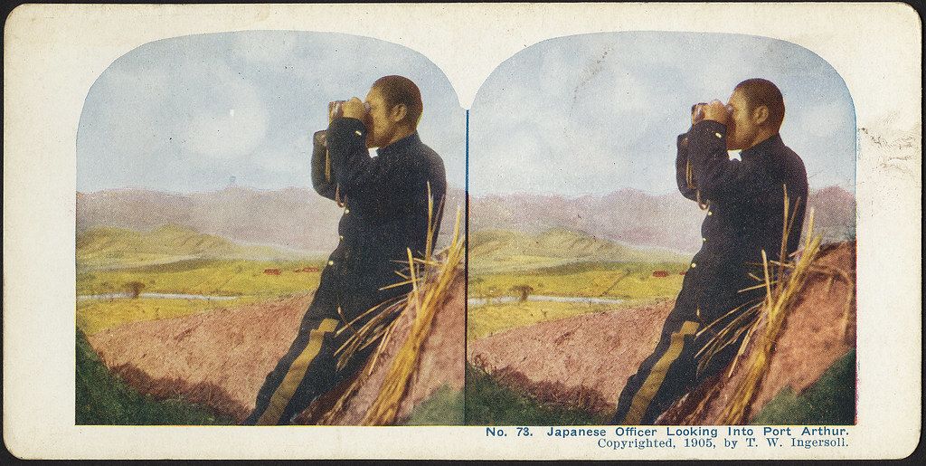 Stereoscopic photograph of a Japanese officer looking through binoculars in a field, with mountains in the background. The image is labeled “No. 73. Japanese Officer Looking Into Port Arthur. Copyrighted, 1905, by T. W. Ingersoll.”