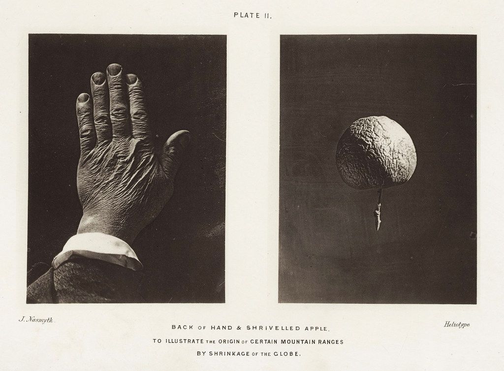 Vintage black and white photographic plate showing a hand and a shriveled apple, illustrating the origin of mountain ranges by shrinkage of the globe.