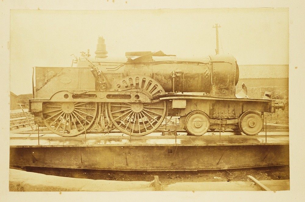 Sepia-toned photograph of a vintage steam engine train on railroad tracks.