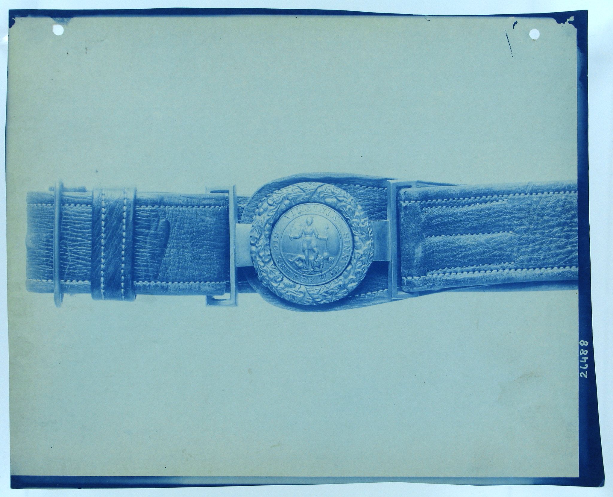 Vintage photograph of a leather belt with an ornate buckle.