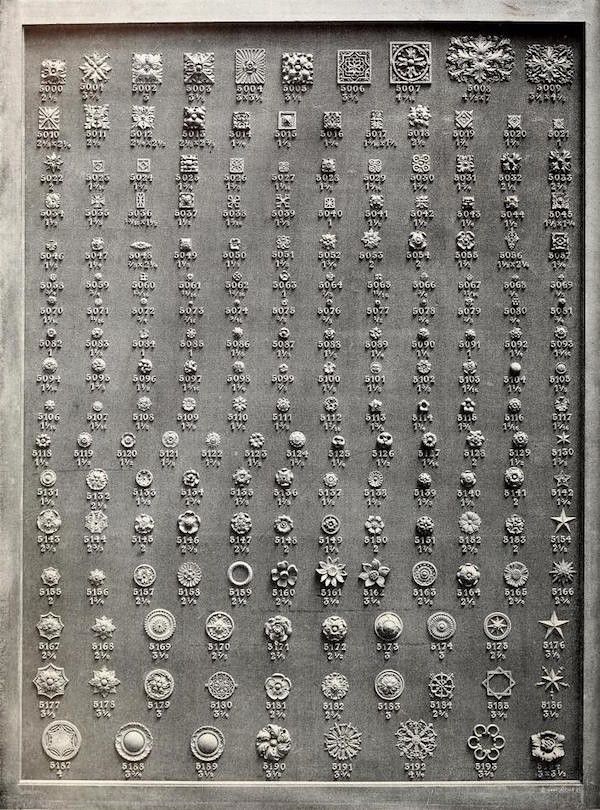 A rectangular metal plate densely covered with a grid of embossed designs, each labeled with a four-digit number.
