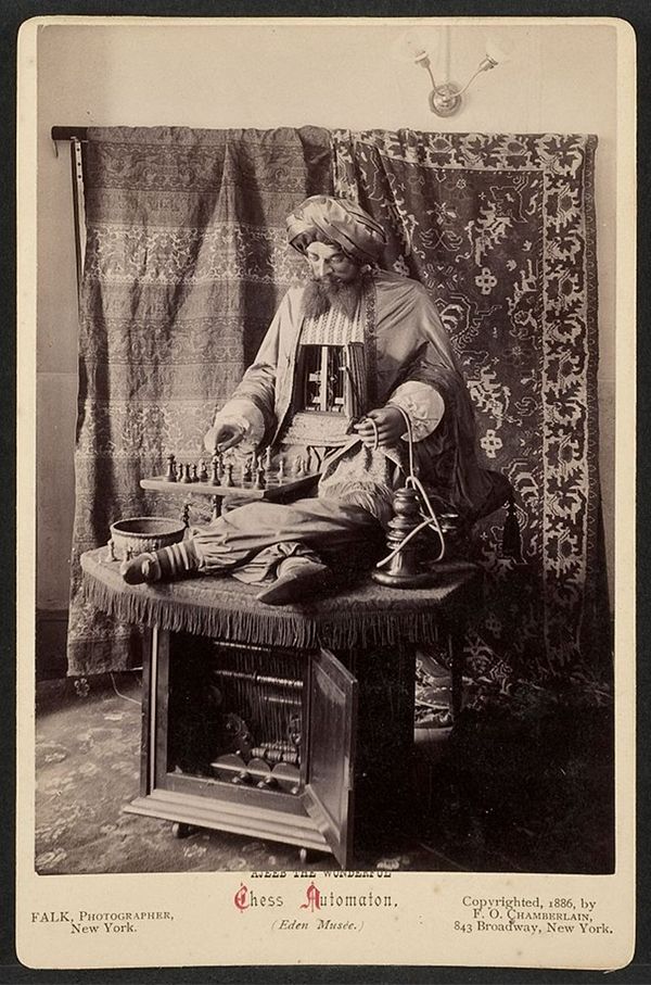 Vintage photograph of a chess automaton, a mechanical figure seated at a chess board, with ornate clothing and visible mechanical parts, labeled 'Azed and the Wonderful Chess Automation' from the 'Eden Musee,' photographed by Falk in New York, 1886.