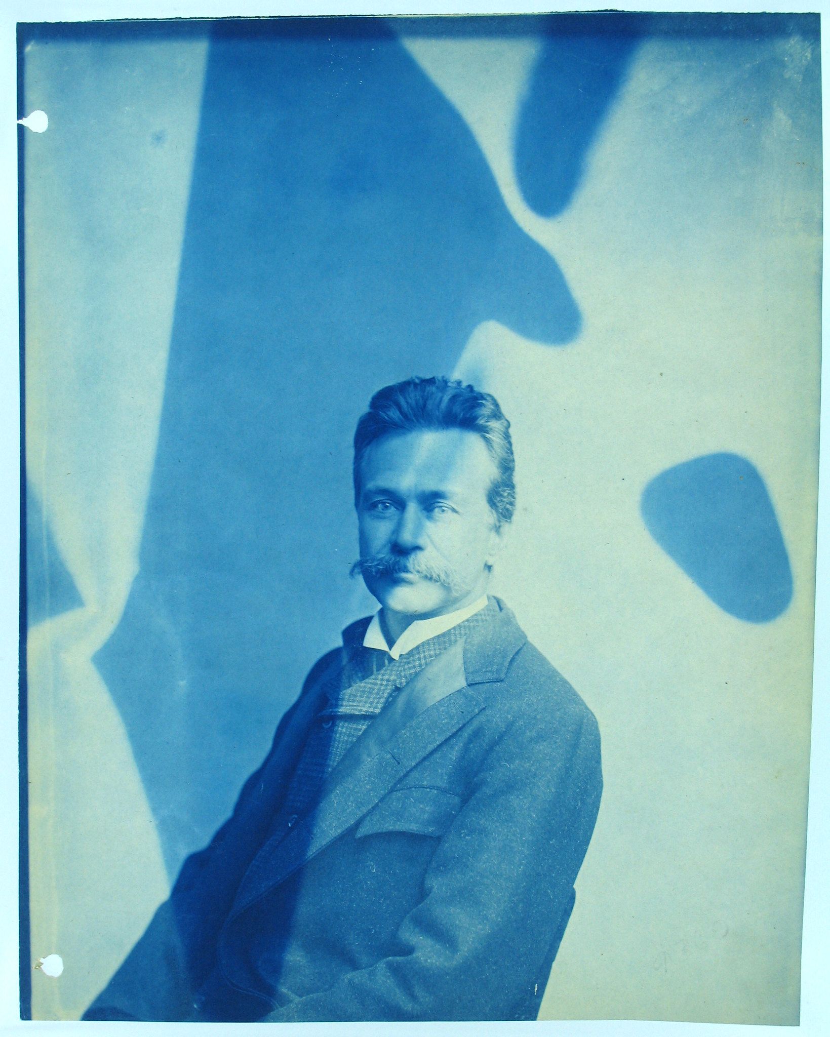 Cyanotype portrait of a man with a mustache and patterned vest.