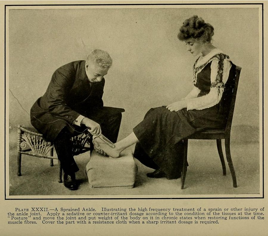 A vintage photograph of a medical treatment scene, showing a man applying a high-frequency treatment to a woman's sprained ankle.