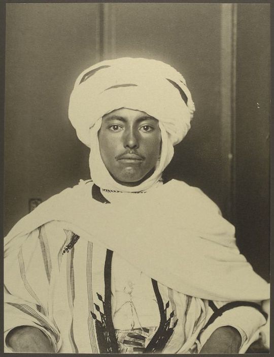 Sepia-toned portrait of a man wearing a white turban and striped robe.