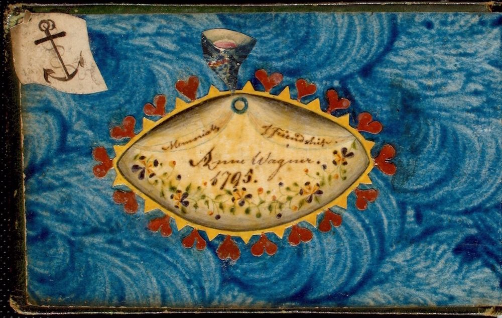 Close-up of a decorated surface with an oval egg-shaped object, red hearts, and an anchor symbol.