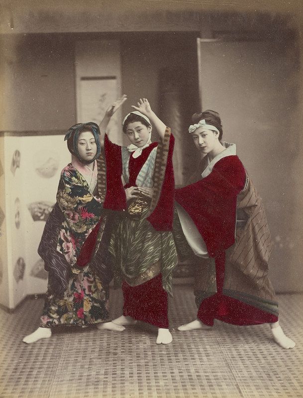 Vintage photograph of three Japanese women in traditional attire posing in a room with tatami mat flooring.