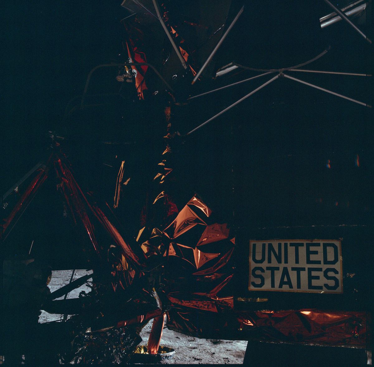A low-angle shot of a complex red metal structure with a sign that reads "UNITED STATES" in the lower right corner.