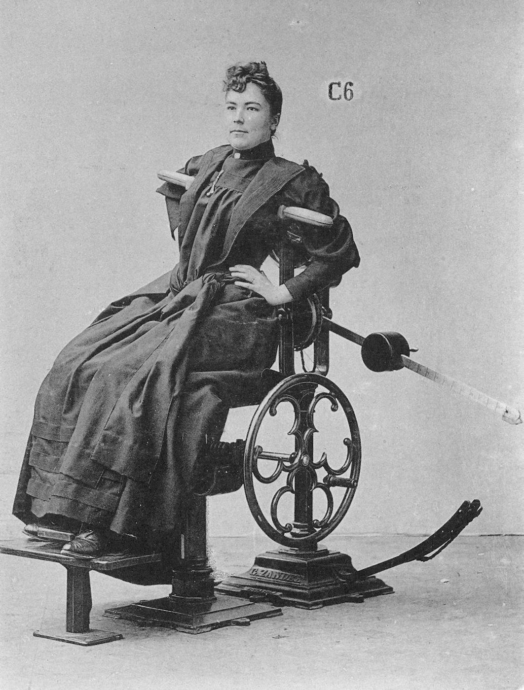 A vintage black and white photograph of a woman seated in a peculiar mechanical device.