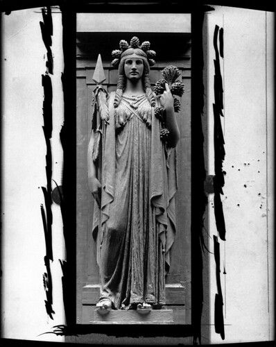 Black and white photograph of a statue of a woman in a doorway.