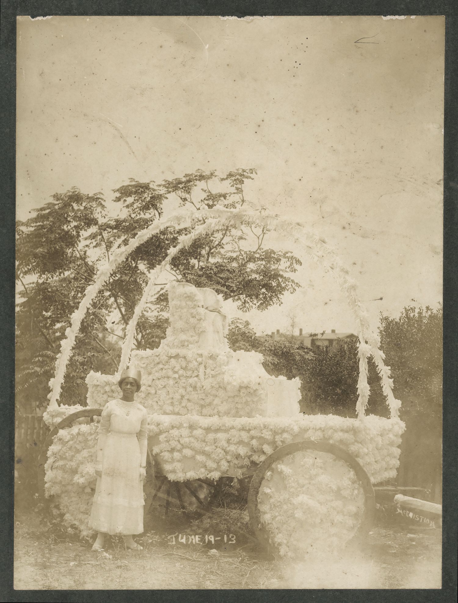 A sepia-toned photograph from June 19, 1913, depicting a decorated float with a person standing in front of it.