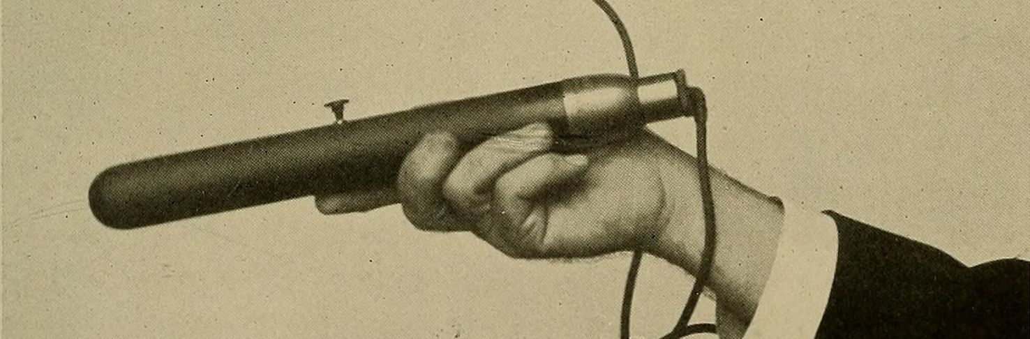 Close-up of a hand holding a cylindrical device with a cable attached.