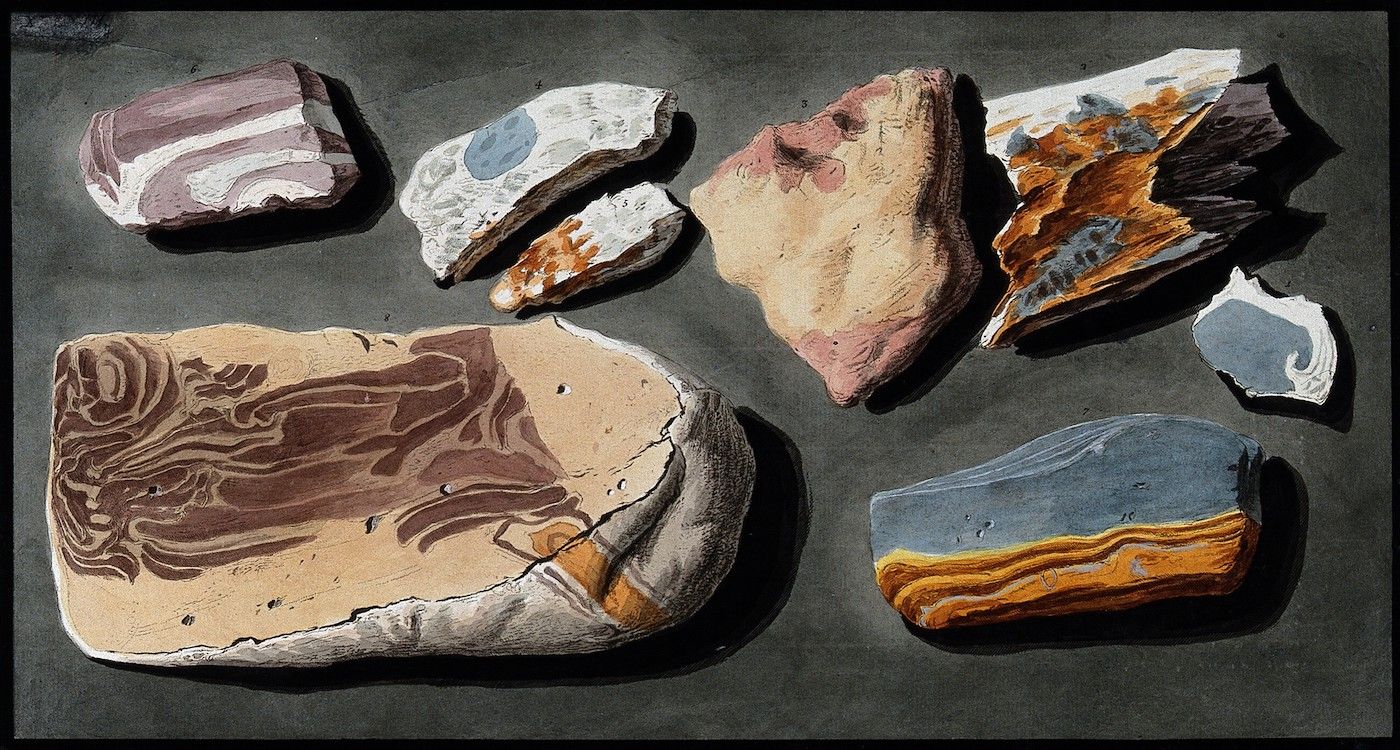 A collection of stone fragments, likely flint, arranged on a dark, textured surface.