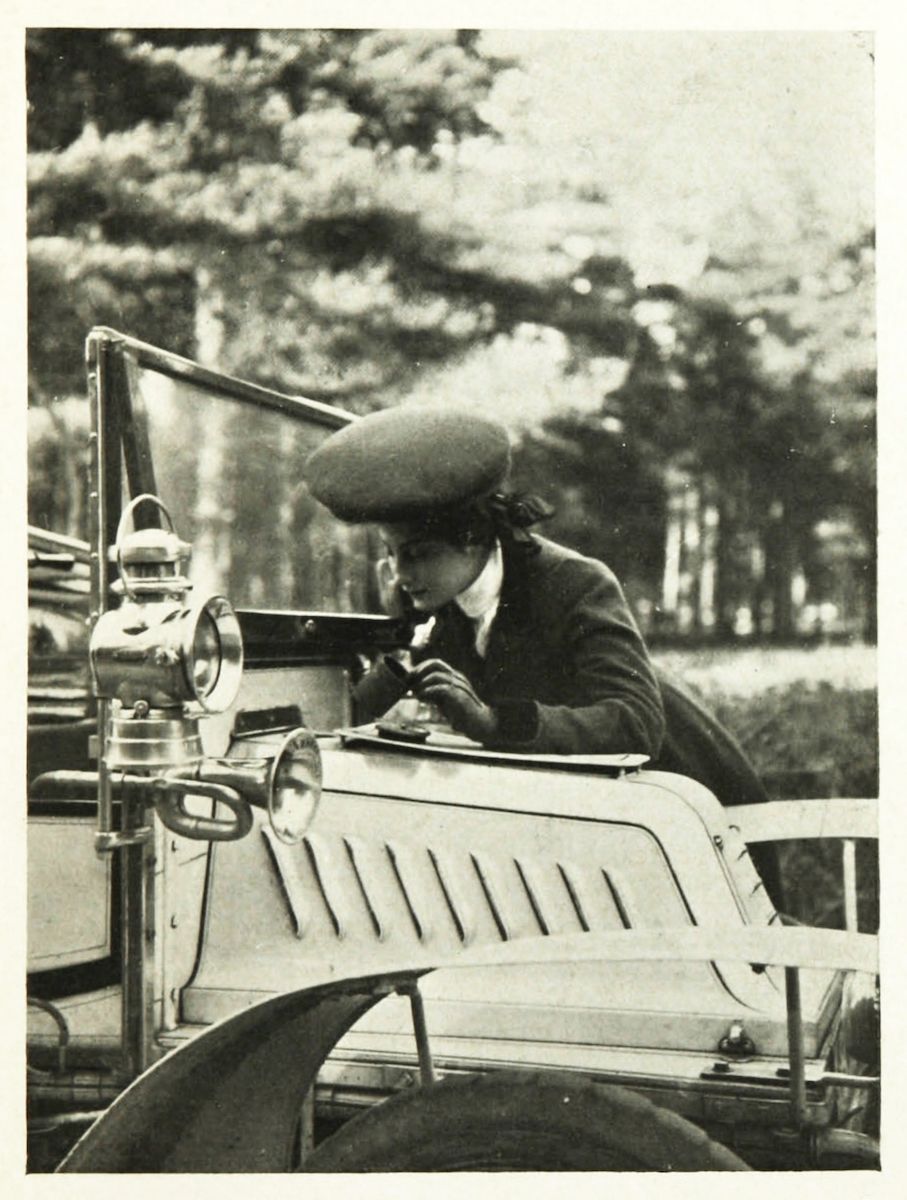 Vintage black and white photograph of a man driving an early automobile.